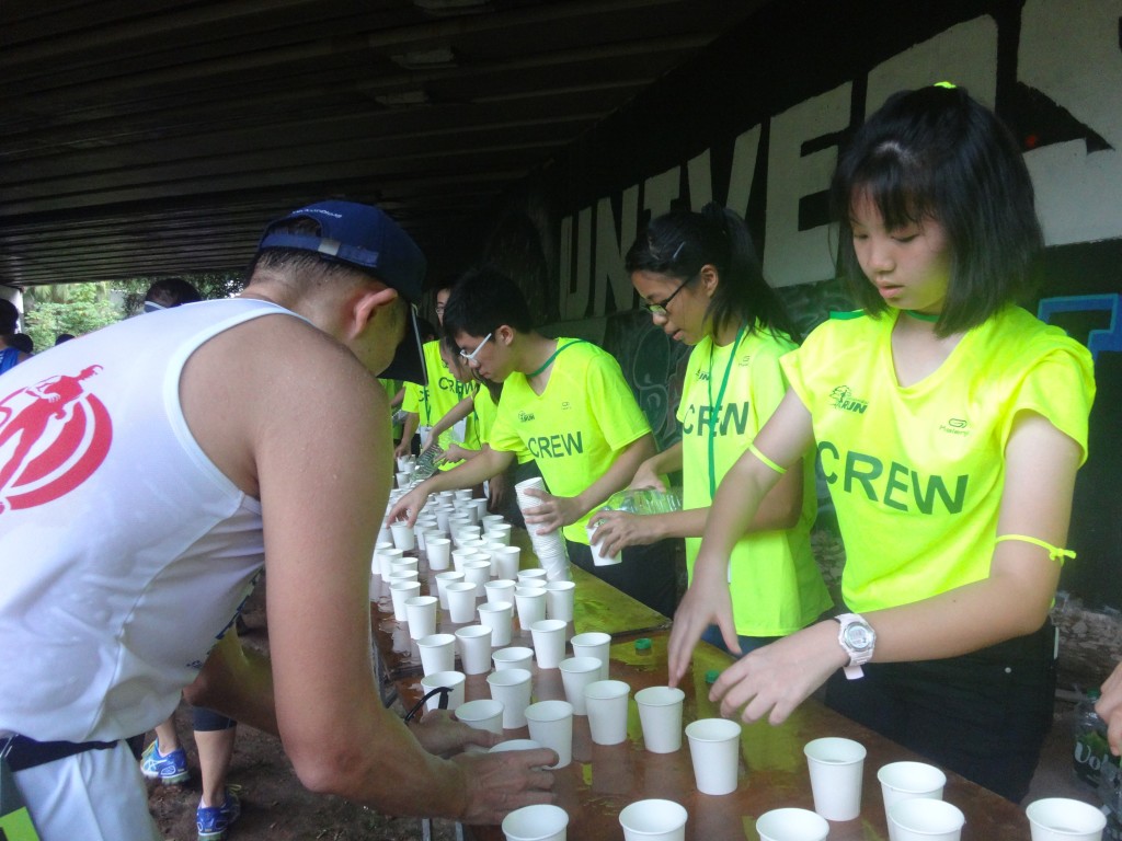 A runner grabs a cup of water from the hydration station.