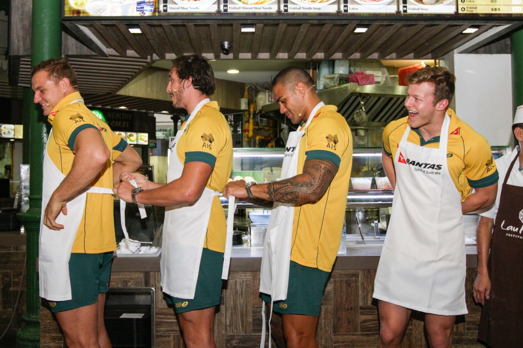 The players help each other to put on the aprons. [Photo credits to Song Tao, Imagica Production.]