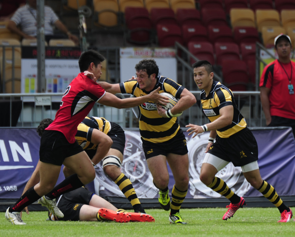 An SCC player (Black & Yellow) attempting to break through a tackle from a player from the Singapore National Team (Red) during the plate quarter-finals. (Photo Credit: Singapore Cricket Club) 